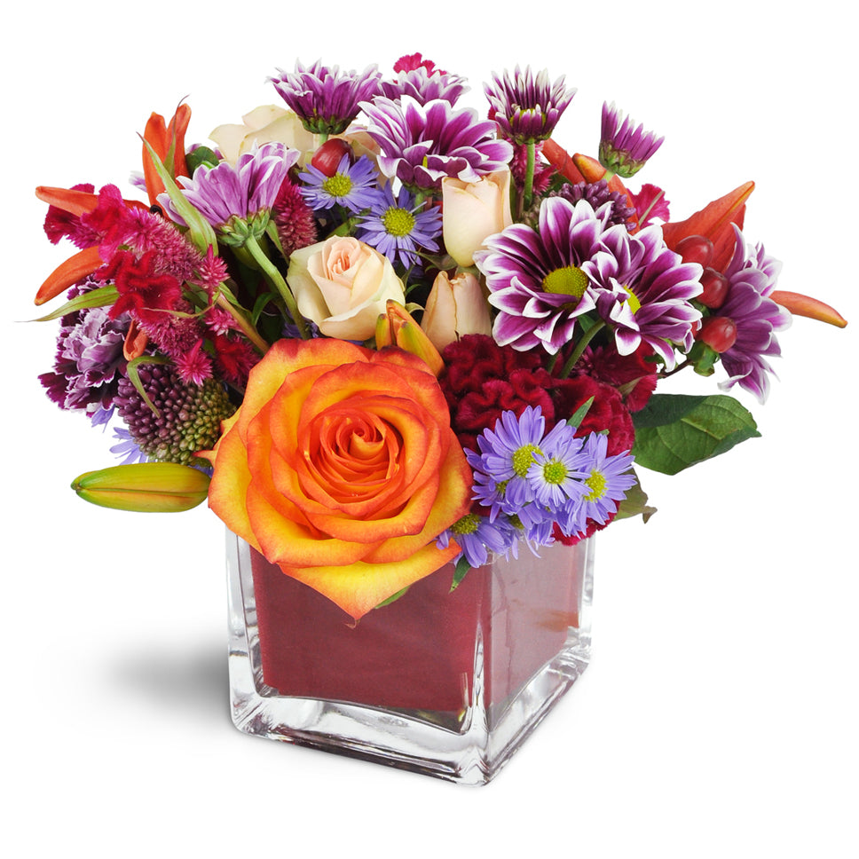 Remarkable Red!™. Roses, lilies, spray roses, and more are arranged with care in a modern cube vase.