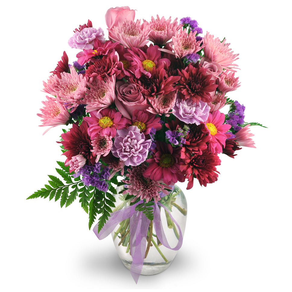 Purple Moon - Standard. Roses, carnations, chrysanthemums, and statice in shades of pleasing purples are expertly arranged in a clear rose vase.