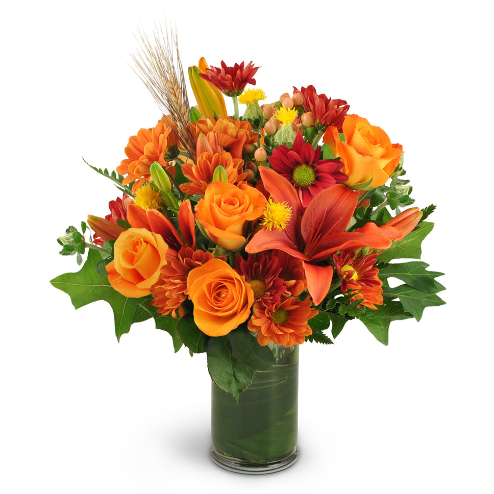Autumn Awakening a deluxe flower arrangement - features orange lilies, roses, safflower, chrysanthemums, and hypericum berries—along with wheat, oak leaves, and aspidistra.