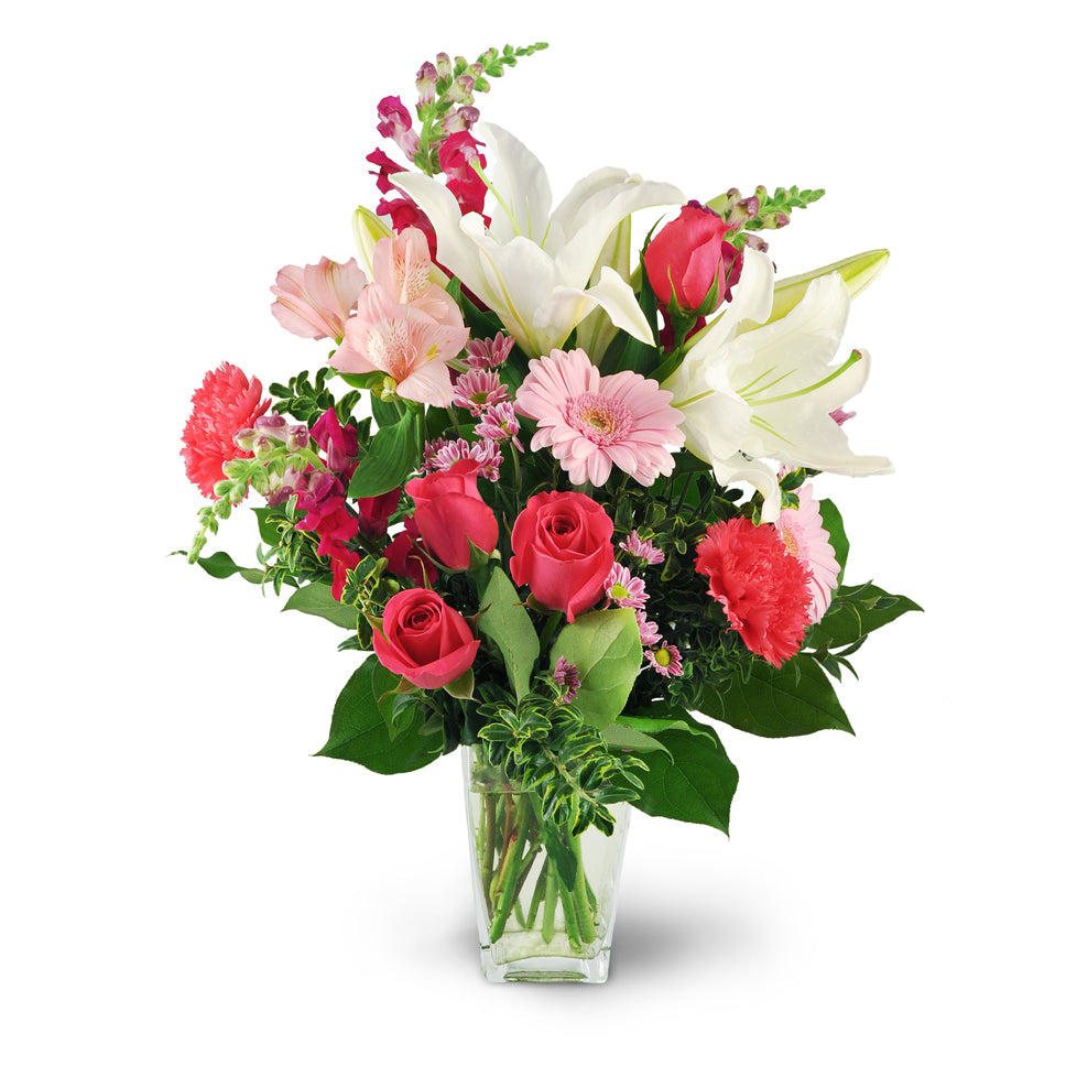 Love Blooms. White oriental lilies, pink roses, carnations, mini Gerbera daisies, snapdragons, alstroemeria, and chrysanthemums are arranged in an elegant glass vase.