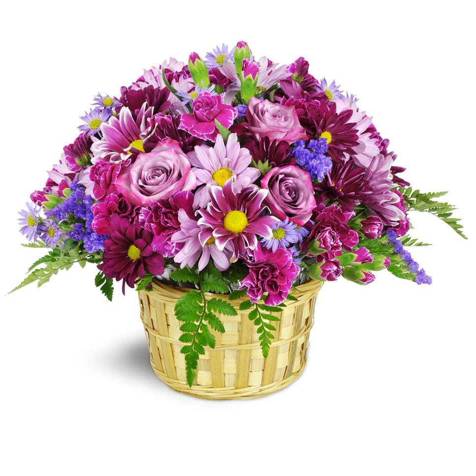 Amethyst Skies Basket premium flower arrangement. Daisies, carnations, asters, miniature carnations, and more—are beautifully arranged in shades of lavender and deep plum.