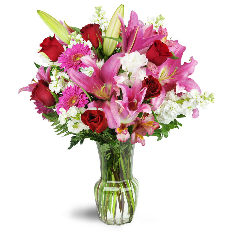 Blushing Heart Bouquet - premium flower arrangement. Deep red roses, lush lilies, and pretty pink Gerbera daisies are arranged in a clear glass vase.