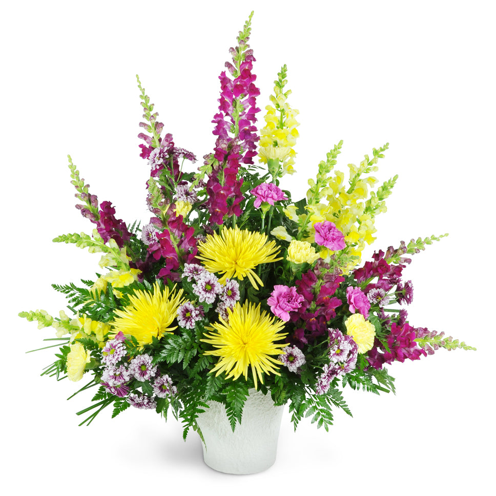 Warm Remembrance. Beautiful snapdragons, fuji mums, and carnations are arranged in various shades of purple and yellow.