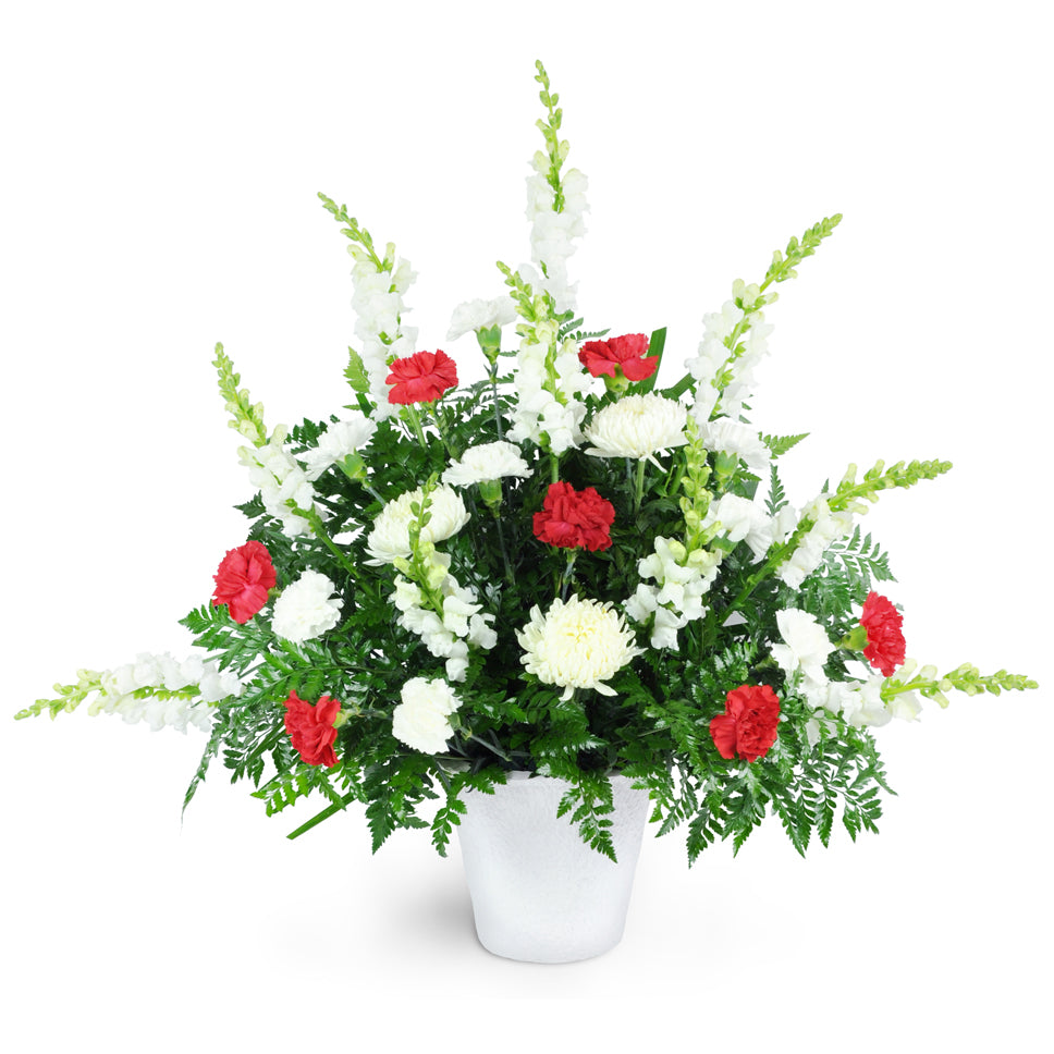 From the Heart. Pure white snapdragons and commercial mums are accented with red carnations to create a graceful display at the funeral home or service.