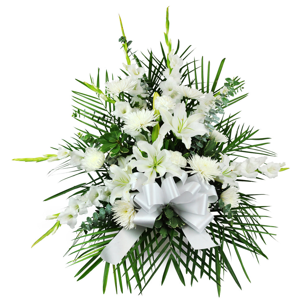 Calming Comfort floral arrangement. Lilies, mums, gladiolus, eucalyptus, and more are arranged in a tribute for the funeral home or service.