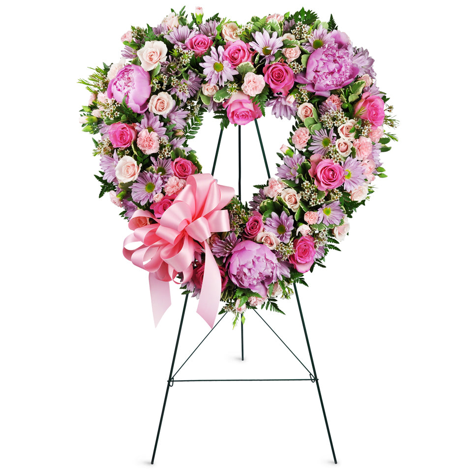 With Open Hearts™. Roses, peonies, daisies, and more are elegantly arranged for display at the funeral home or service.