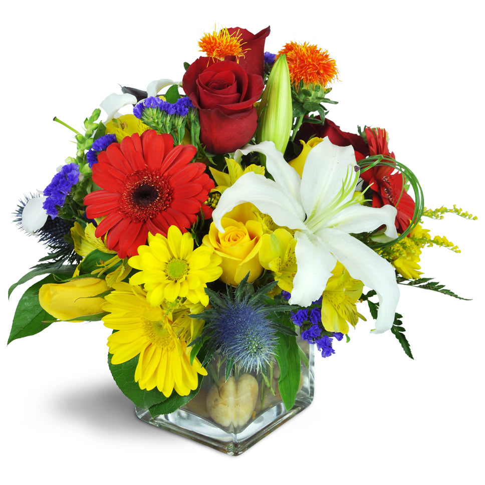 We're Walking on Sunshine. Roses, Gerbera daisies, lilies, alstroemeria, and more are arranged in a glass vase.