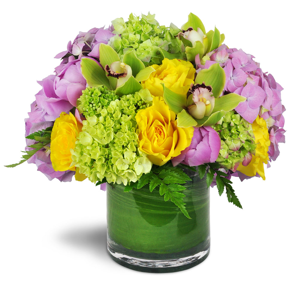 Summer's Bounty Vase™. Green and pink hydrangeas, yellow rose blooms, and distinctive green Cymbidium orchids are arranged in a glass vase.