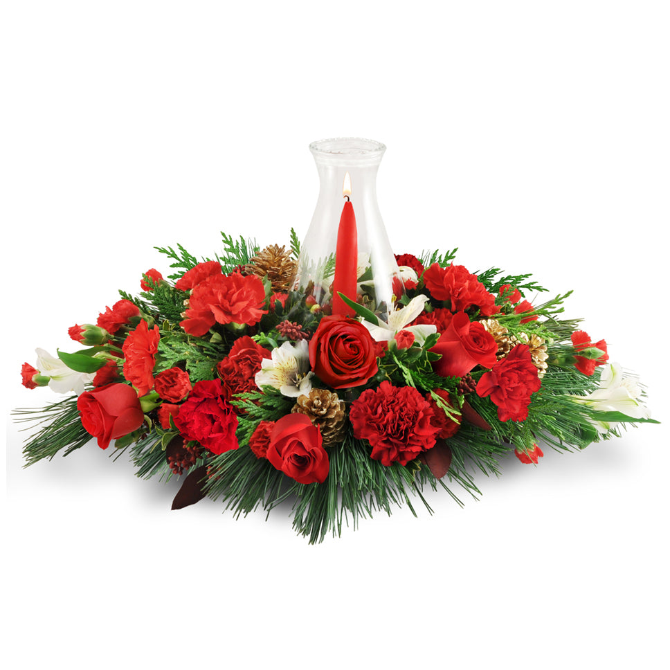 Warming Glow - Premium. Carnations, alstroemeria, pinecones, cedar, and more are topped with a taper candle in a delicate hurricane glass.