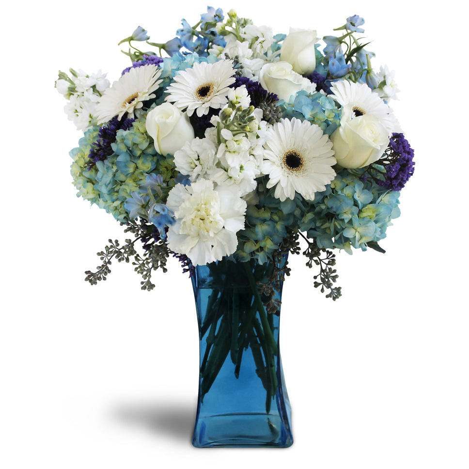 Blooming Blues flower arrangement. Hydrangeas, Gerbera daisies, roses, and stock are arranged in a glass vase.