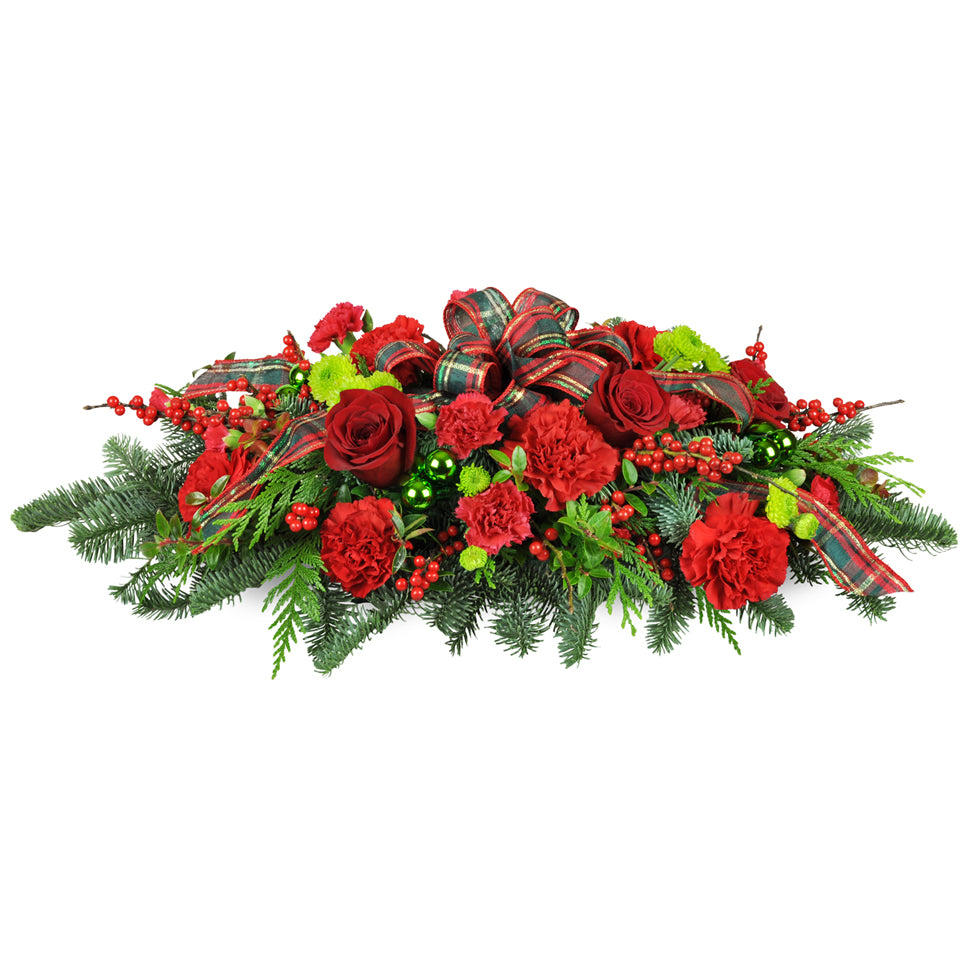 Christmas Traditions Centerpiece™ - Premium. A classic swag is arranged with red carnations, green baubles, pine, cedar, and more.