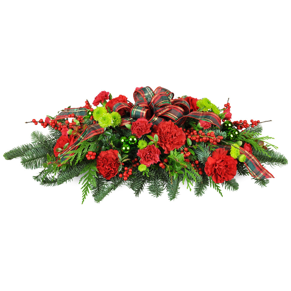 Christmas Traditions Centerpiece™ - Deluxe. A classic swag is arranged with red carnations, green baubles, pine, cedar, and more.