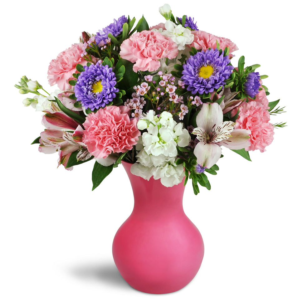 Perky Pinks™. Treat them to a bouquet of pink carnations, delicate stock, and purple asters in a charming vase.