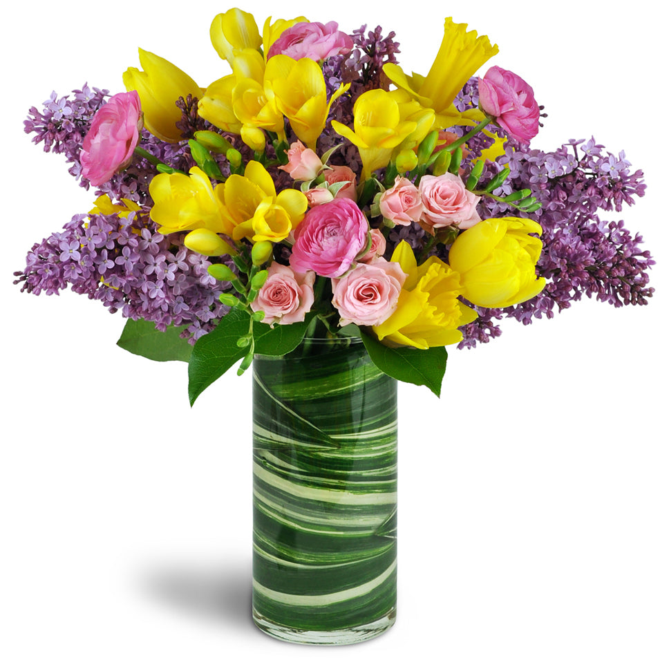 Spring Smiles™. Lilacs, tulips, and more are gorgeously arranged in a glass vase.