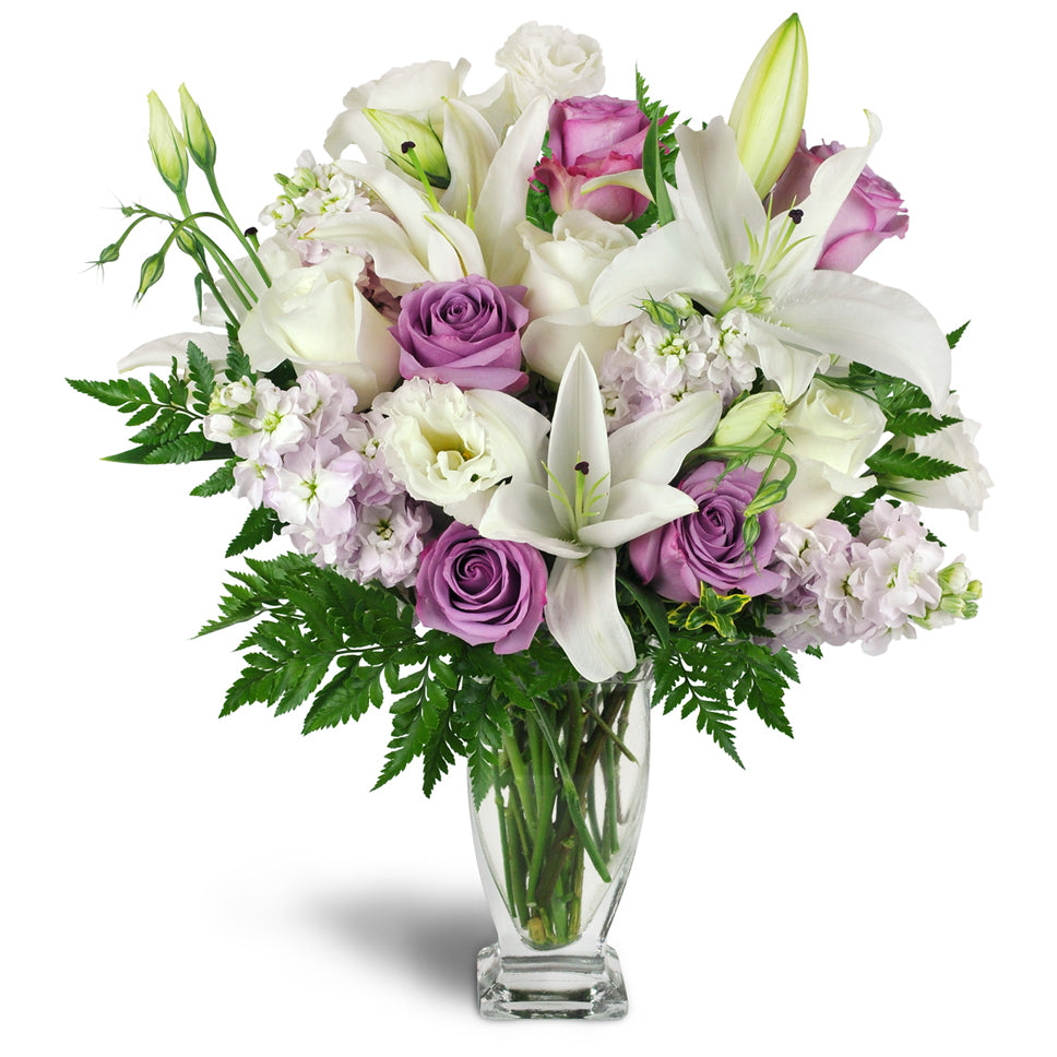 Sweet as Sugar Bouquet™ - Standard. White and lavender roses are arranged with Asiatic lilies, stock, lisianthus, and more in an elegant glass vase.