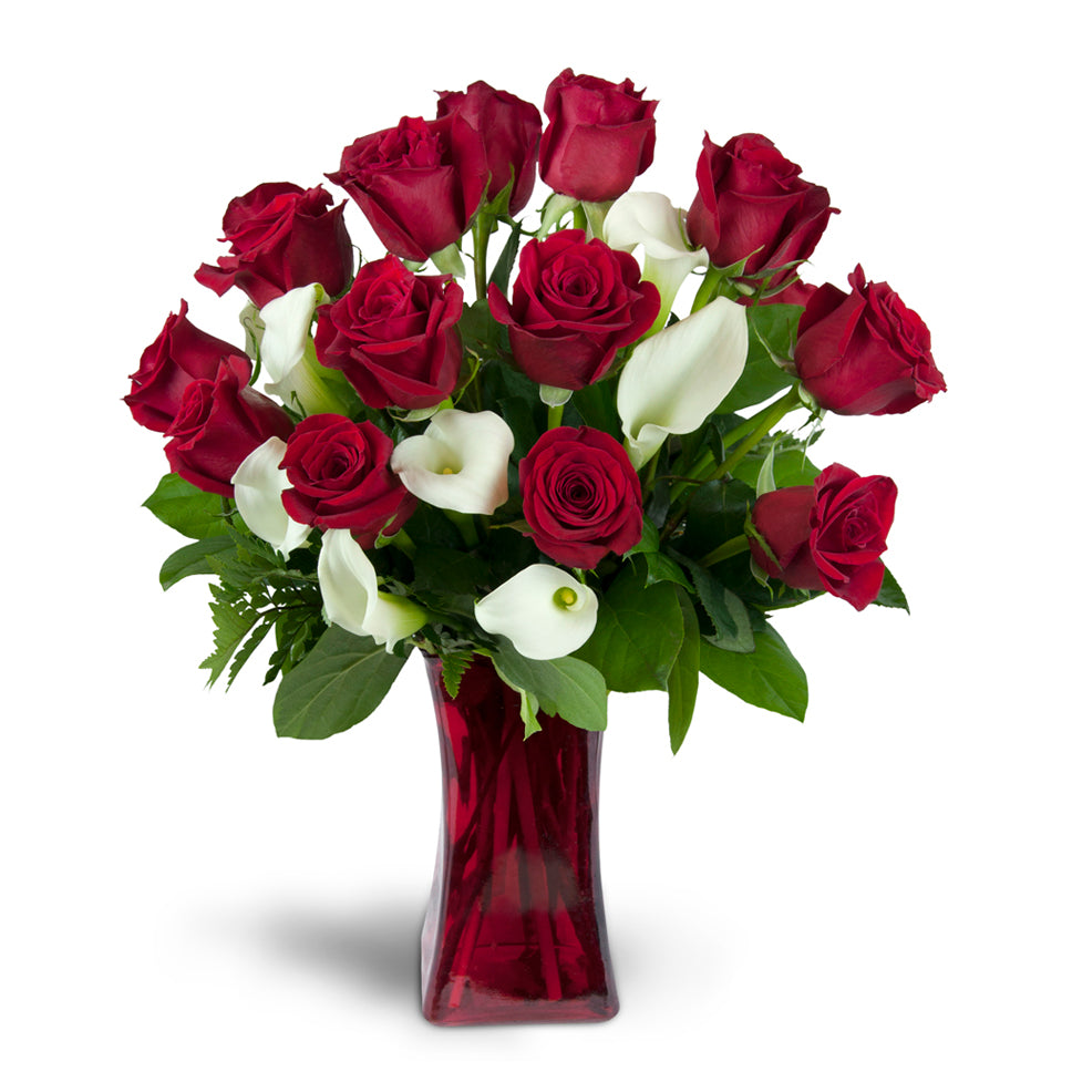 Full of Love™ - Deluxe. Classic red roses and mini Calla lilies are elegantly arranged in a glass vase. Upgrade to Premium to add large, fragrant lilies.