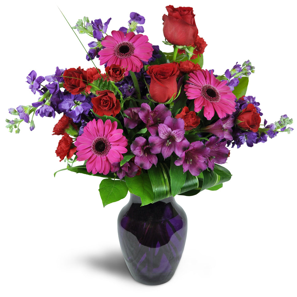Romance Medley™ - Premium. Purple Peruvian lilies are arranged with stunning red spray roses and stock. Upgrade to Deluxe or Premium to add luxurious red roses.