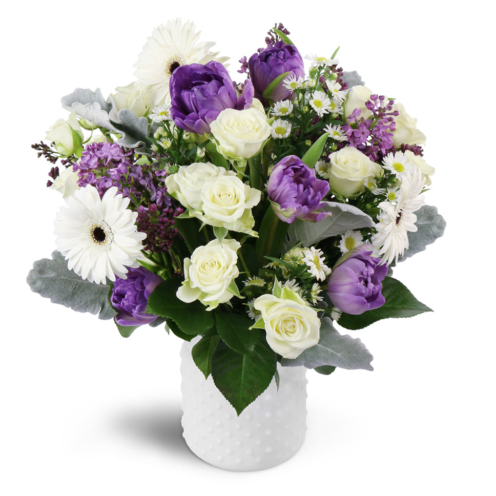 Oasis in Bloom™ - Standard. Featuring white spray roses, purple tulips, and more.