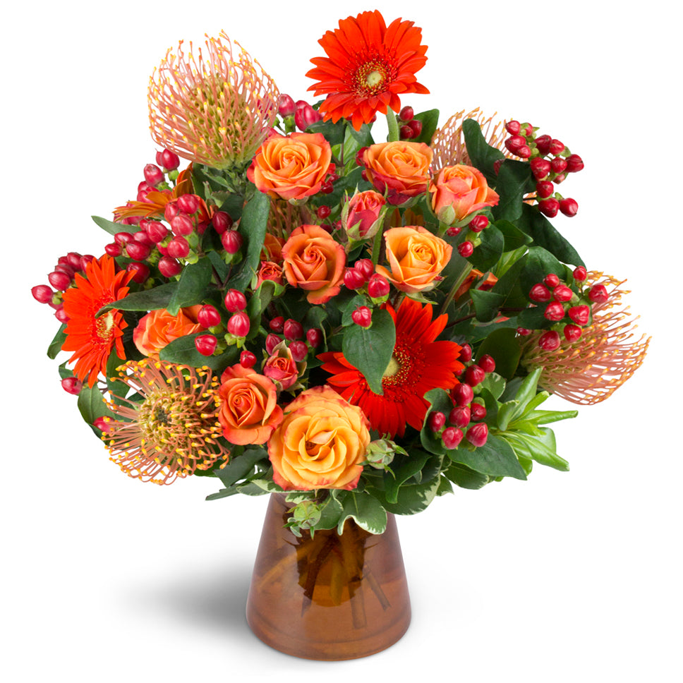 Energetic Orange™ - Premium. Unique pincushion protea are arranged with orange spray roses, mini Gerbera daisies, and more.