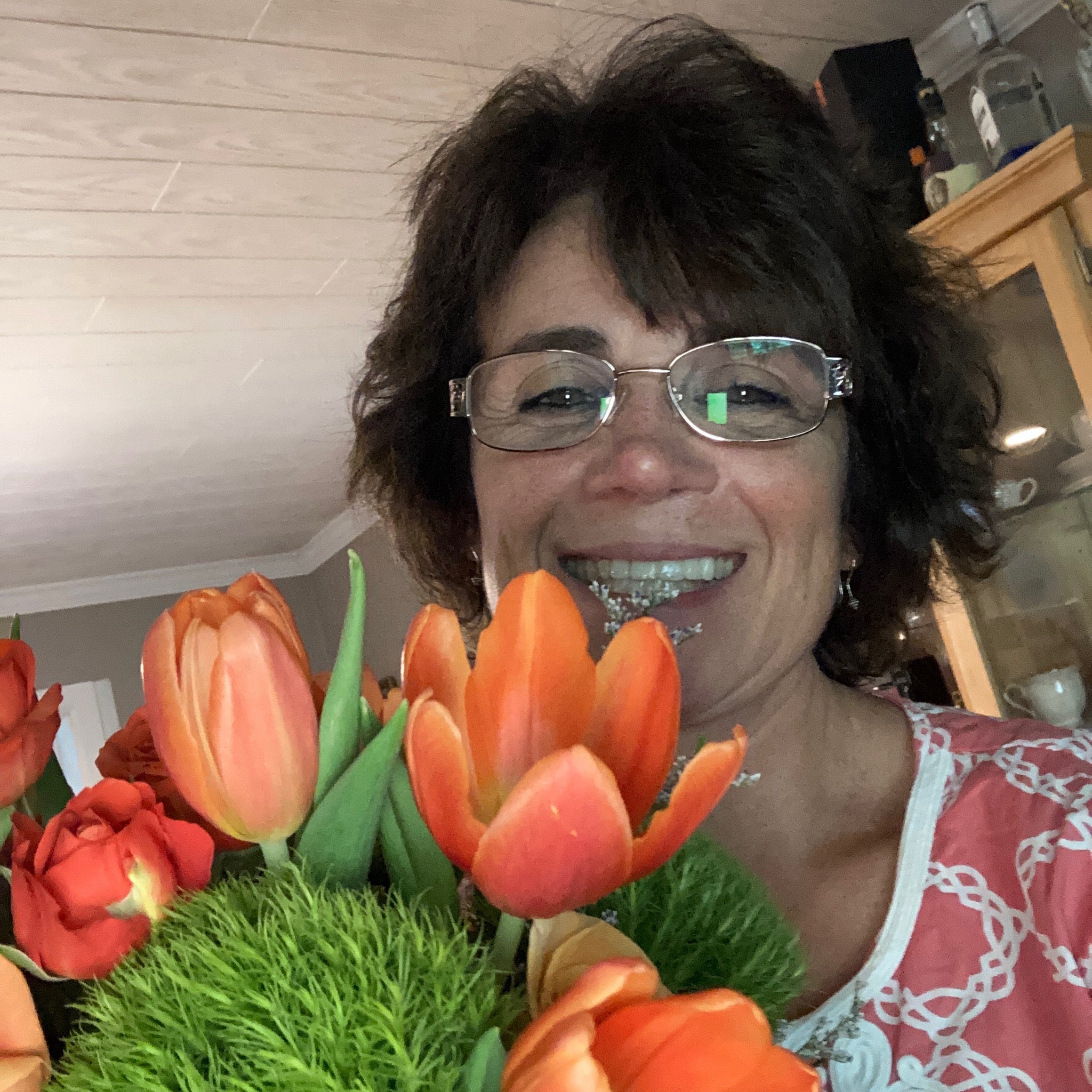 Woman smiling holding her flower arrangement - Autumnal Glory.