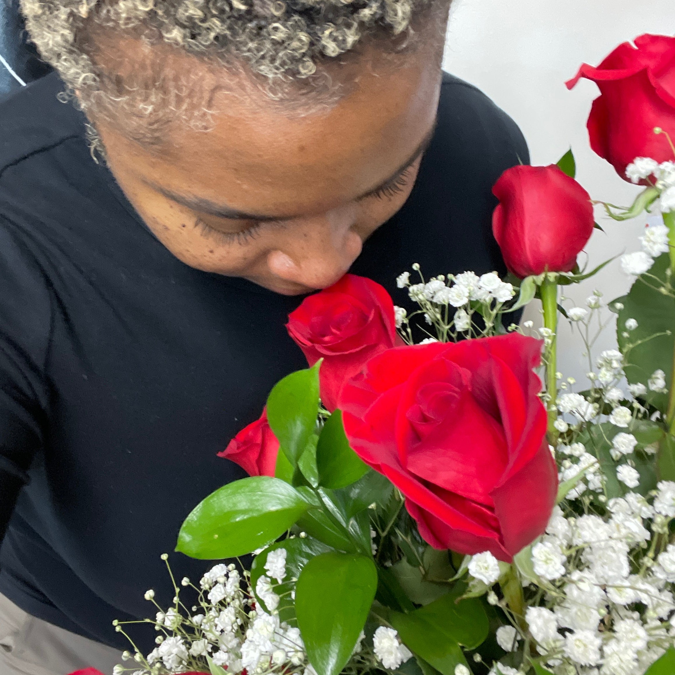 Woman smelling a dozen red roses.