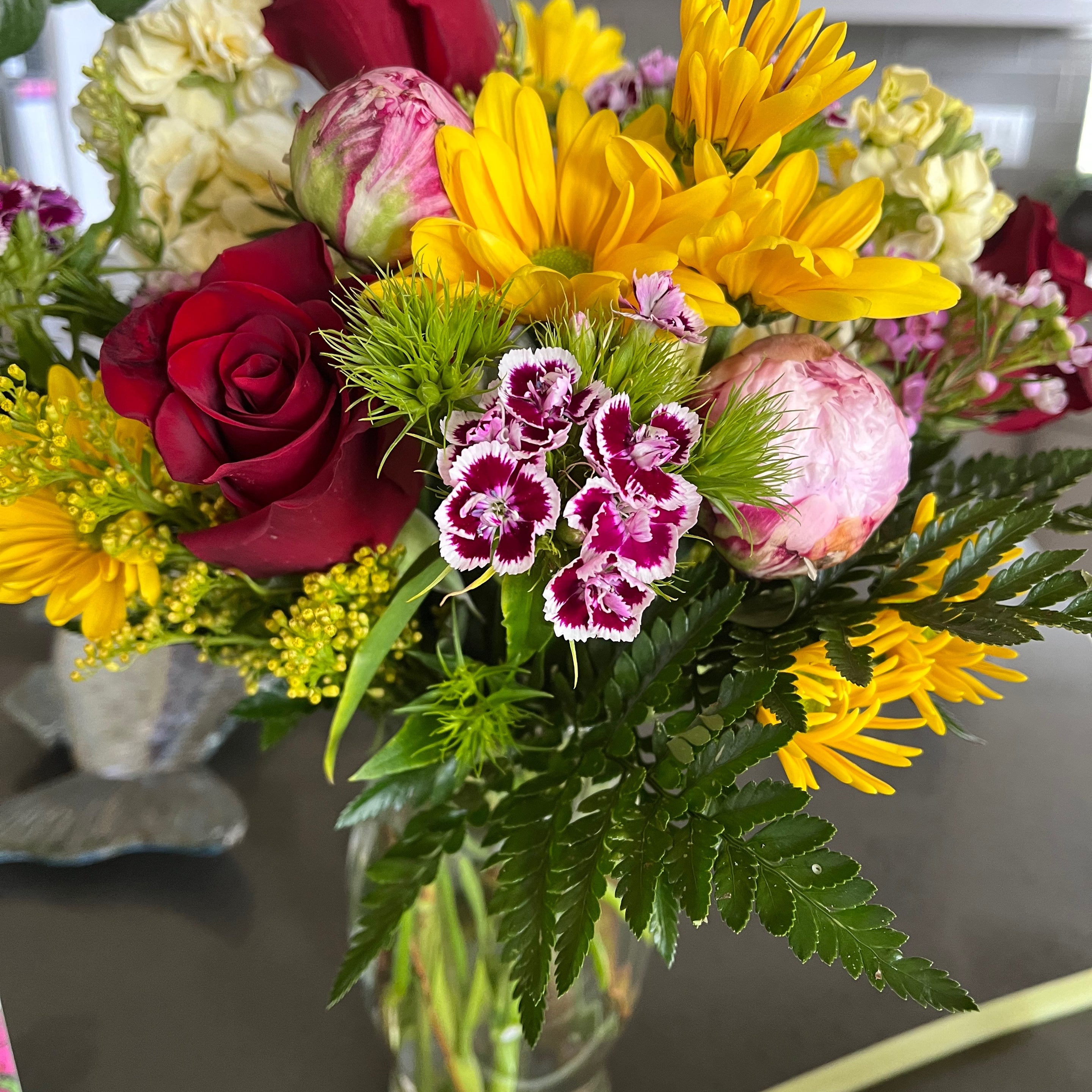 Recipient-submitted photo of a Touch of bliss flower arrangement. Vase on top of table with beautiful bold flowers.