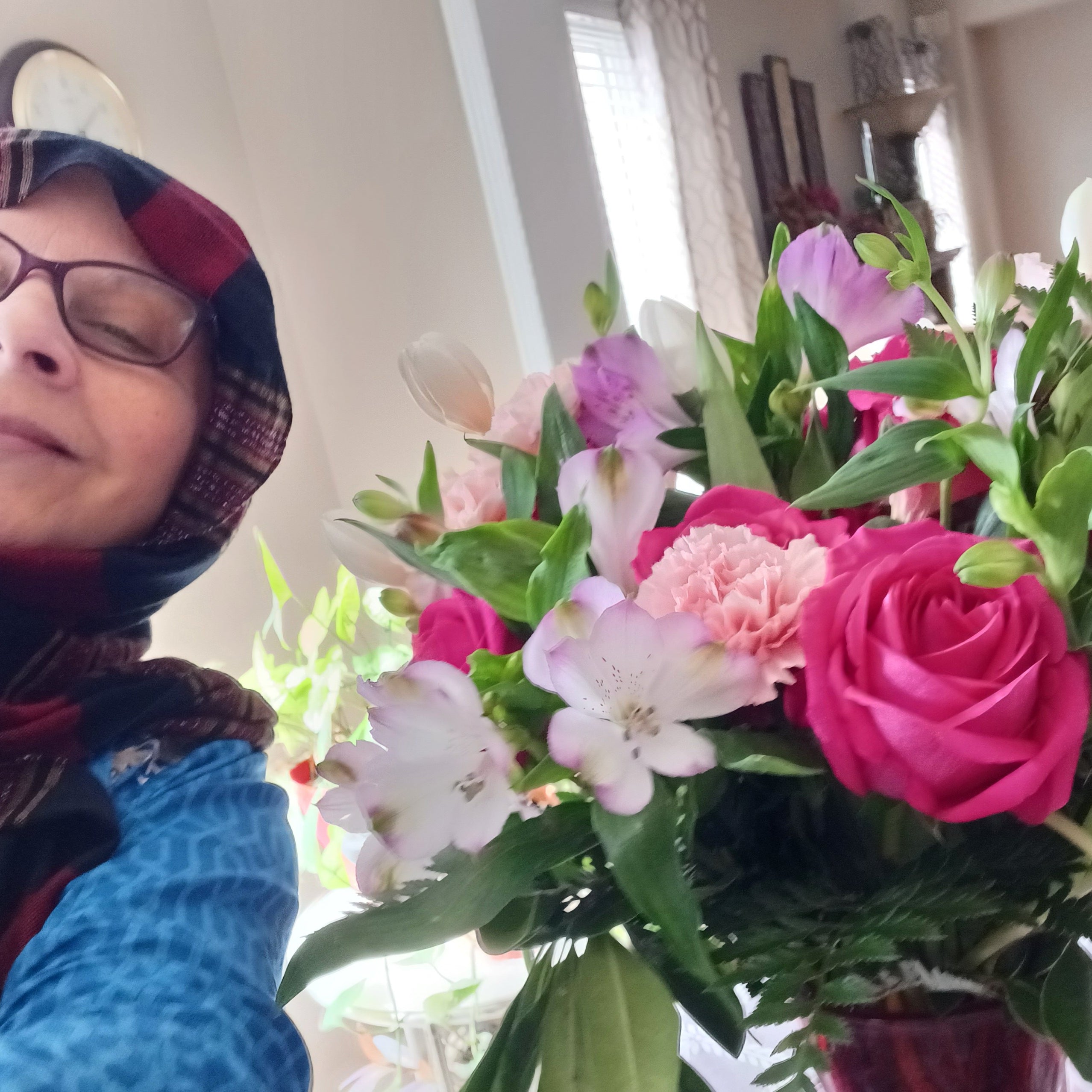 A heartfelt thanks for Berry Perfection flowers. A woman smiling next to her bright flower arrangement full of pinks, purple and green.