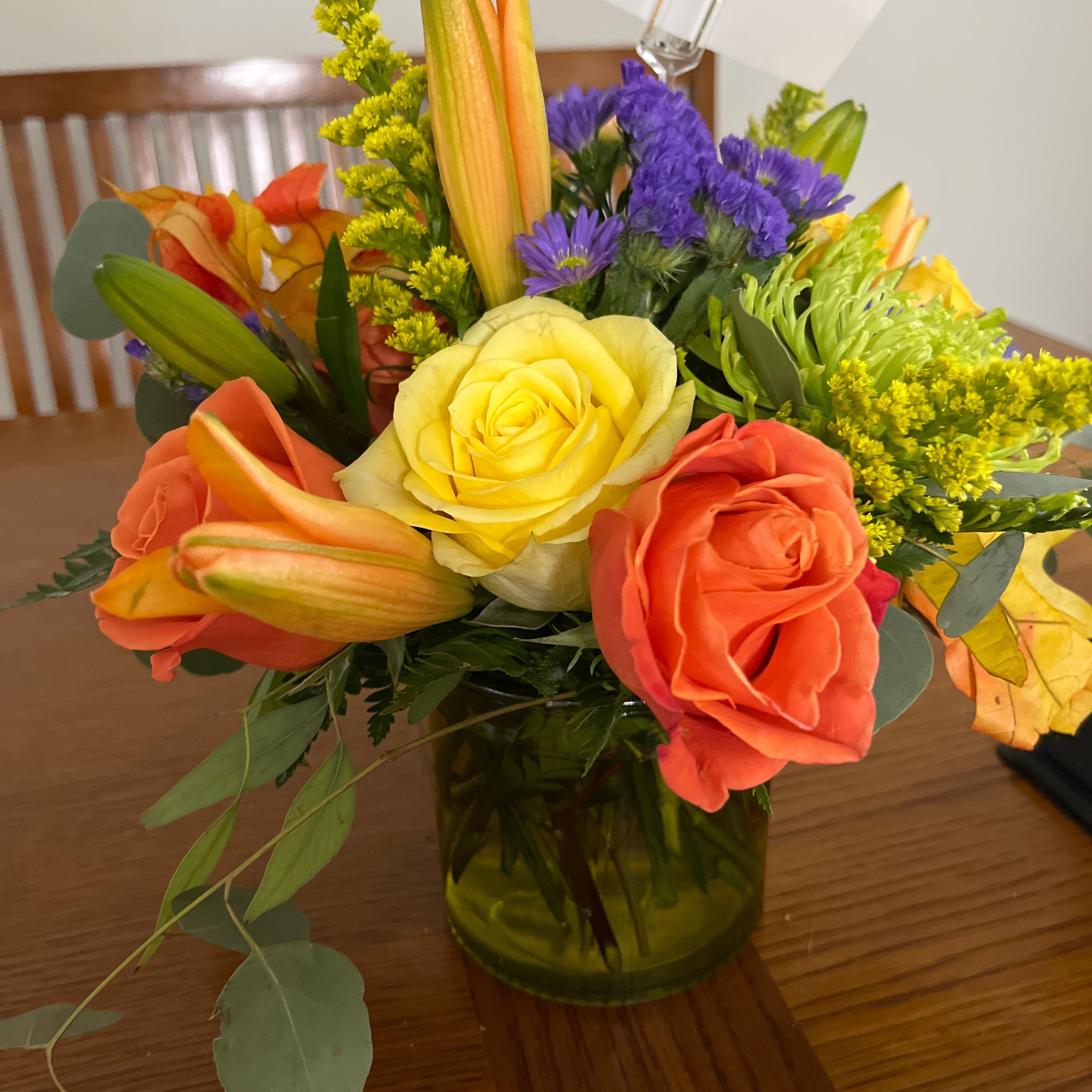 Recipient-submitted photo of Autumnal Glory. Fall themed flower arrangement on top of wooden kitchen table.