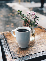 Cup of coffee with vase of flowers