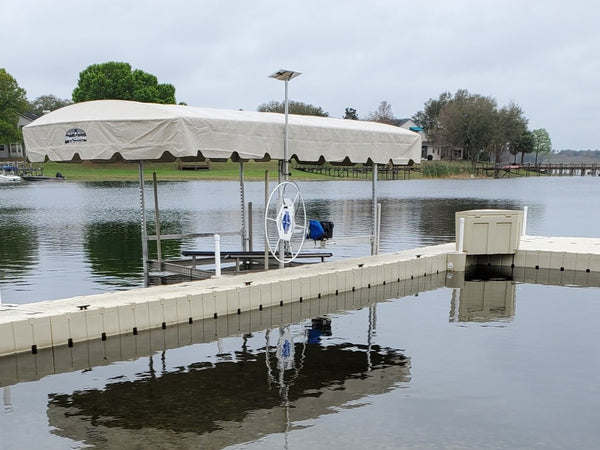A floating dock alongside a free-standing boat lift with a canopy on a lake