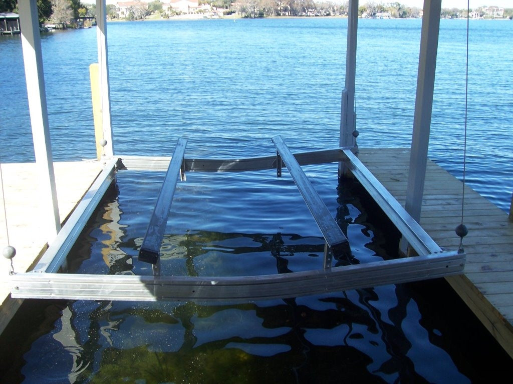 Aluminum boat cradle hanging in a boathouse lift with galvanized steel cables