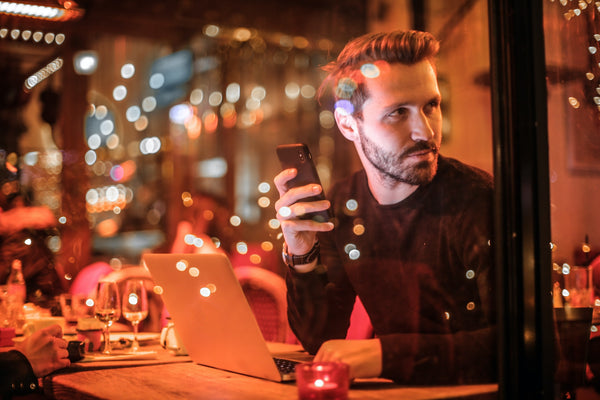 man sits in festive cafe looking at phone