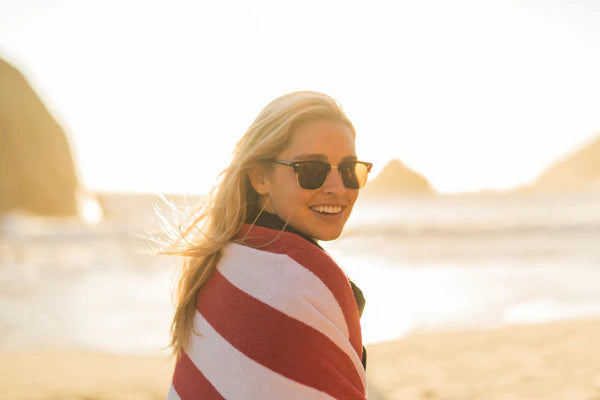 Woman wearing sunglasses standing on a beach in bright sunlight