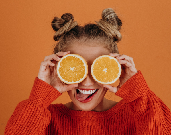 woman holds oranges up to her eyes