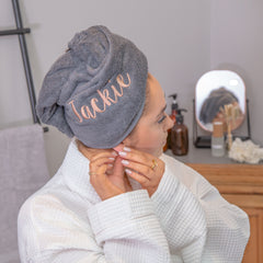 women in spa robe wearing a personalised hair turban putting her jewellery back on