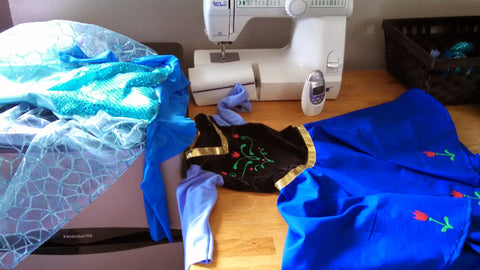 two handmade kids' princess costumes sit next to a sewing machine