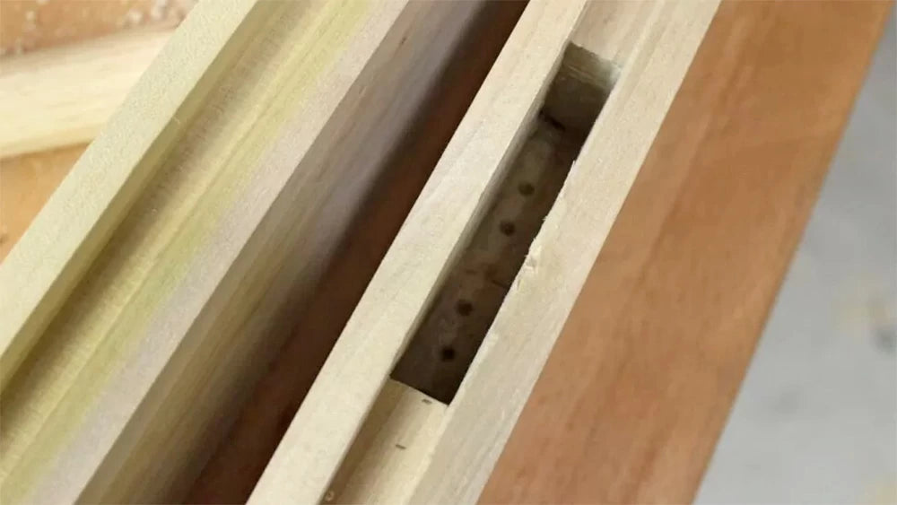 The mortises were created by drilling out the waste with a brad-point drill bit then trimming to final size with chisels. The groove serves as a guide for sizing the width of the mortise.
