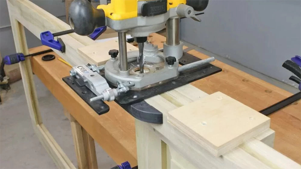 A shop-built jig provides support for the router. The plywood blocks act as stops to limit the length of the mortise to the proper size.