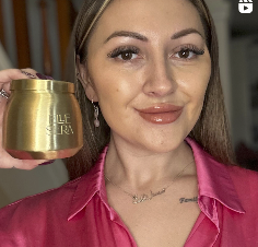 Woman holding a golden jar and smiling at the camera.