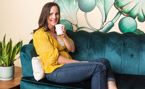 Woman sitting on couch with tea and comfycomfy buckwheat hull pillow