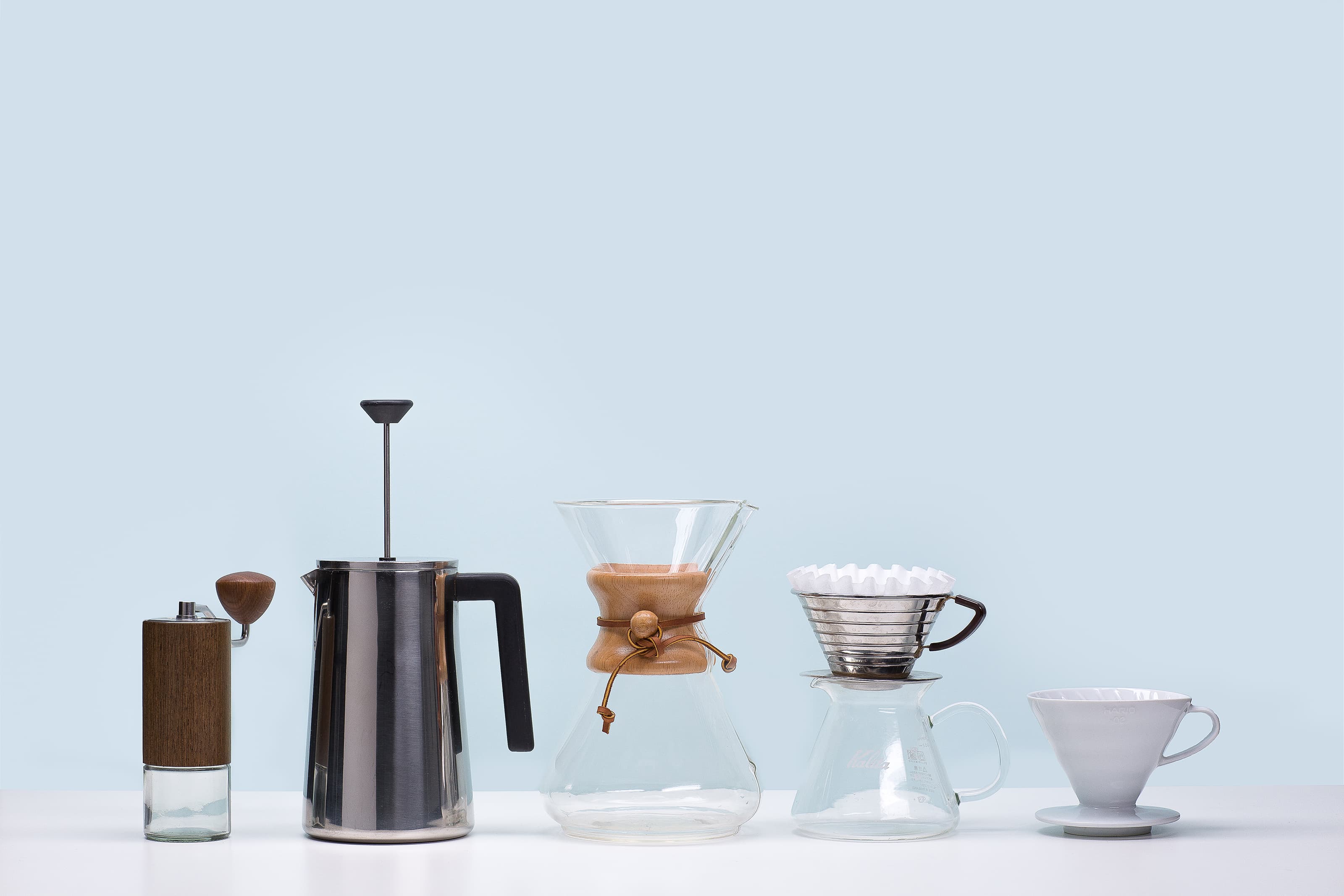 lineup of coffee equipment: handgrinder, percolator, chemex, Kalita Wave, bonmac