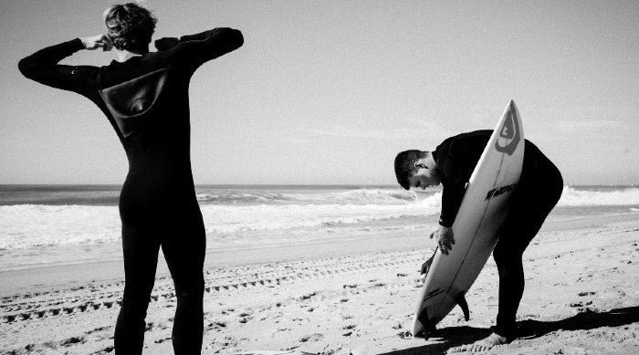 two men putting on their wetsuit