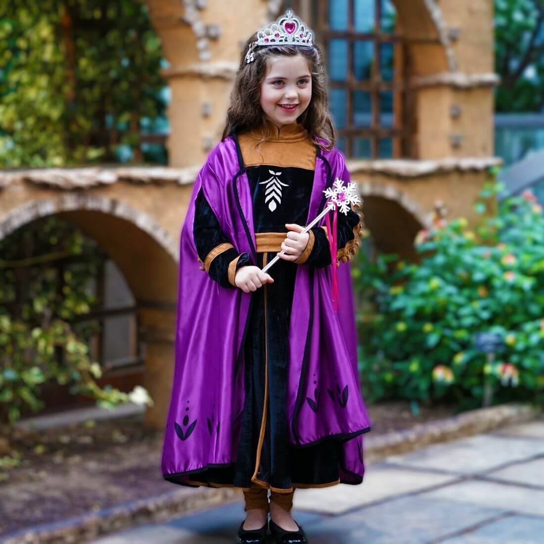 Little girl in a princess costume with a purple cape