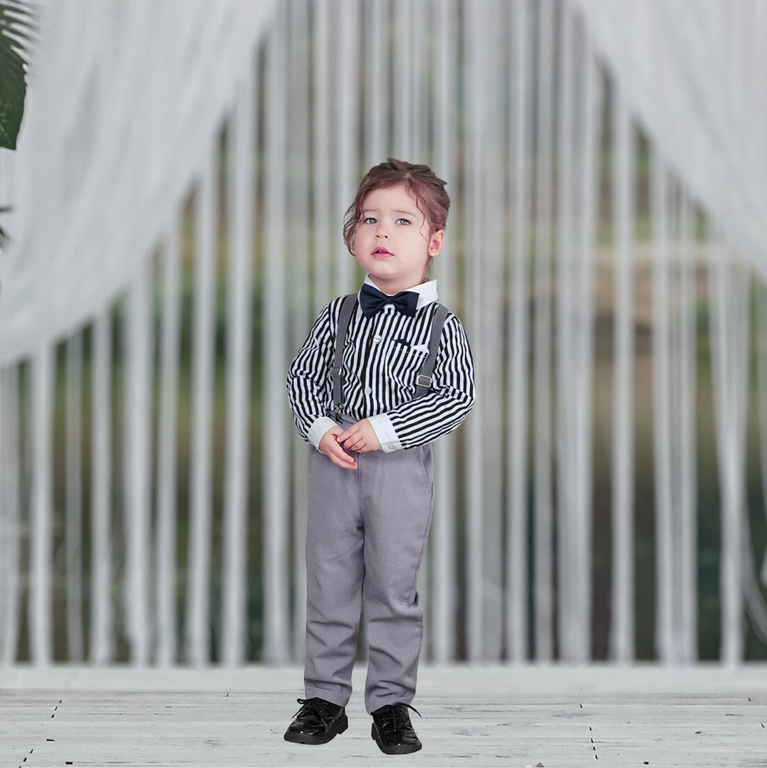 Toddler wearing grey pants and suspenders with striped blue shirt