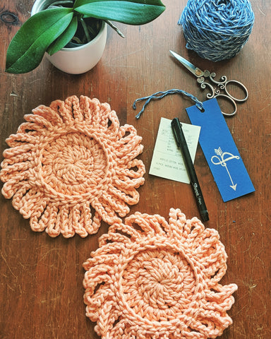 Crochet coasters on a table with a plant