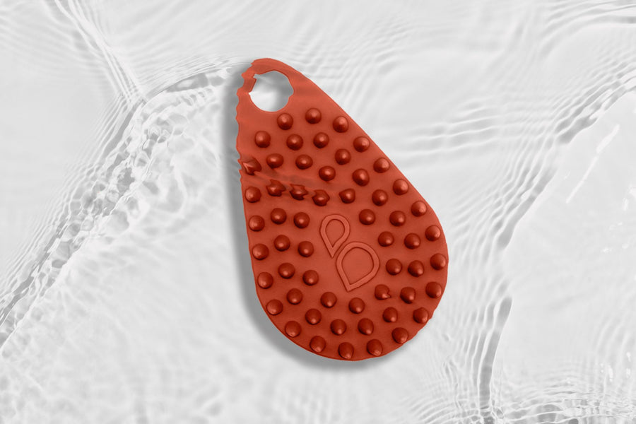 A red silicone scrub under the water against a white background