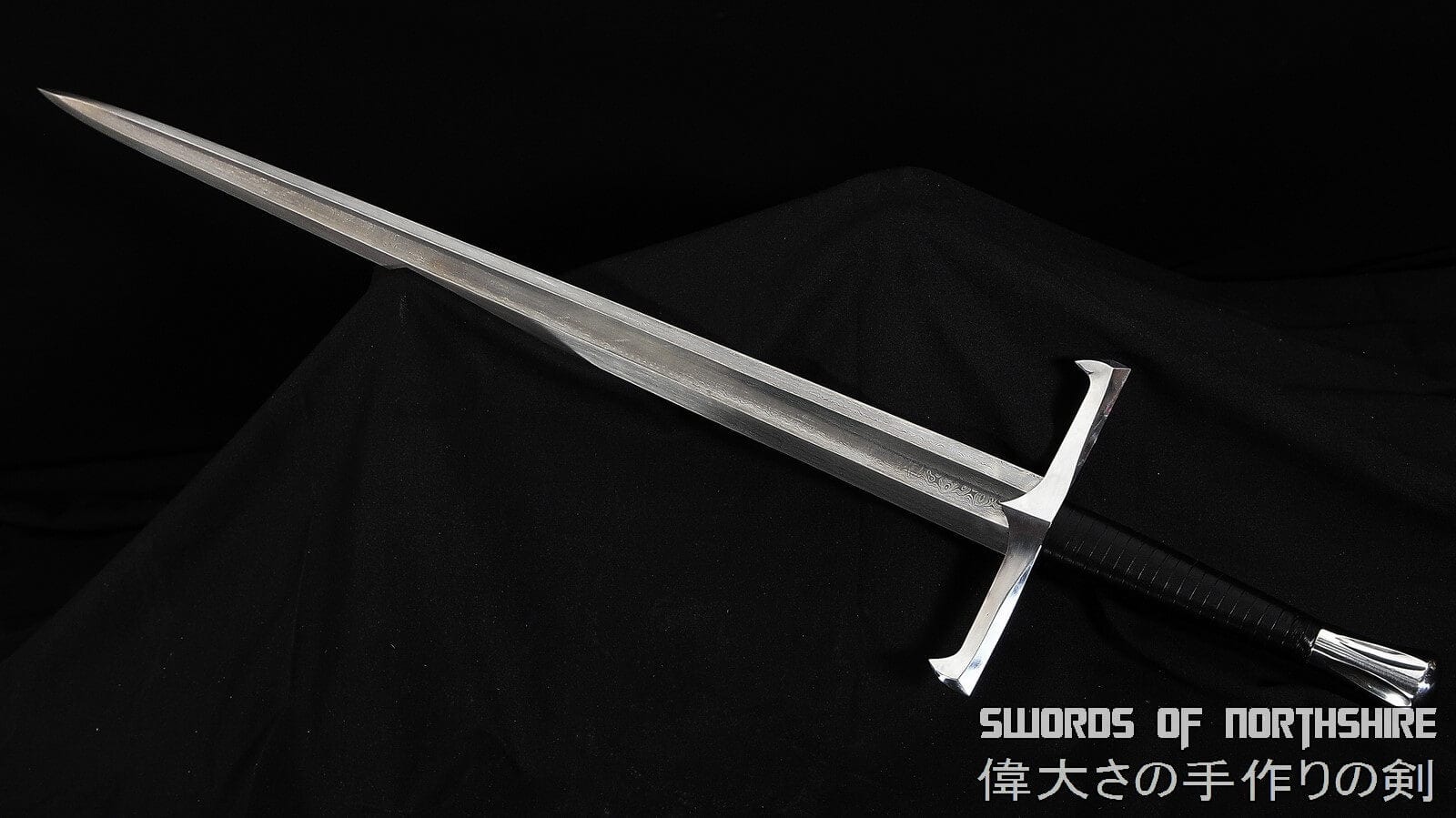 European longsword with a silver blade, silver guard, and black hilt on a black background