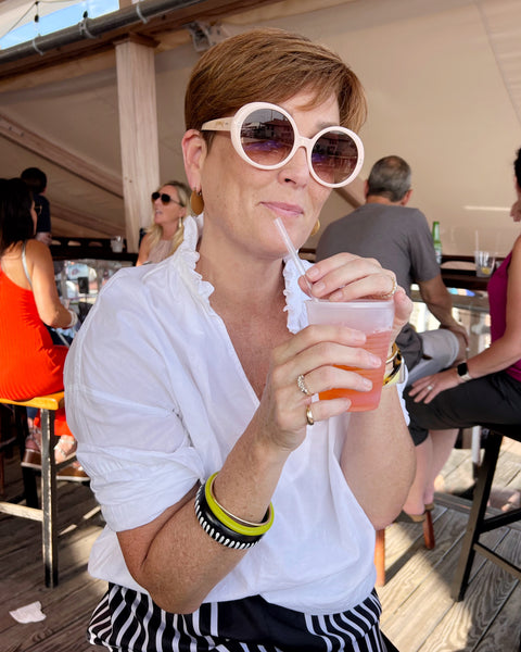 elizabeth wearing sunglasses and sipping a drink