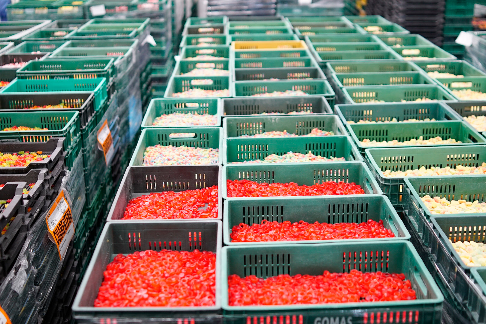 Assorted sugar confectionery products displayed in open green candy boxes in a production setting.