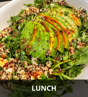 Avocado slices on a bed of quinoa and mixed greens, with a sprinkle of herbs and spices.